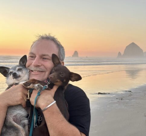 Greg Berman, pictured in Cannon Beach with his rescue dogs Folders and Filene, says his main interest in writing “Bartow,” “is cementing Rick Bartow as a role model for creative people everywhere.” Photo courtesy: Greg Berman