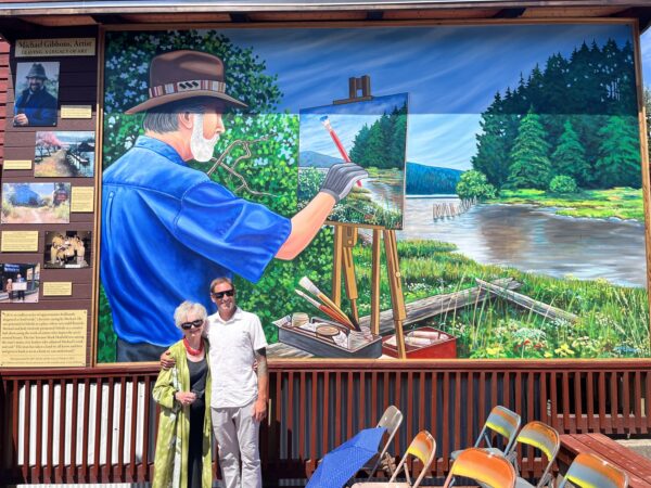 JJudy Gibbons joins muralist Casey McEneny at his painting of her husband, Michael Gibbons, on Toledo's Main Street. A self-guided walking tour of nine murals is among Toledo Art Walk events over Labor Day weekend. Photo courtesy: Michael Gibbons Art